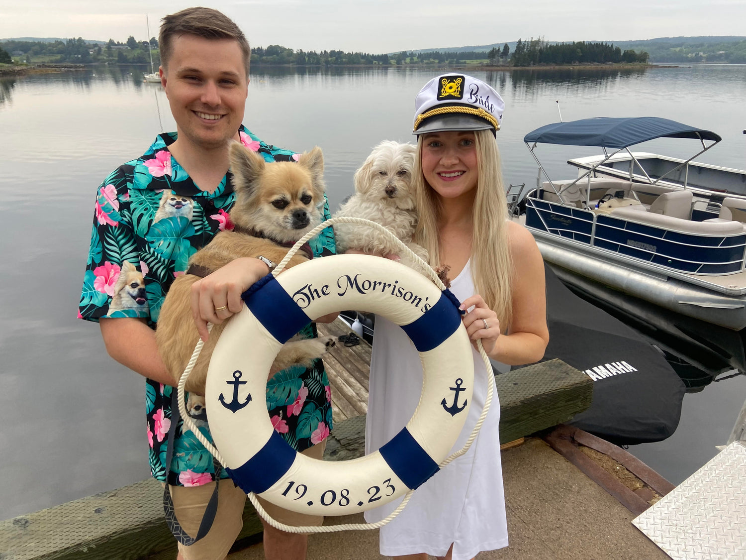 Newly weds Billy and Katherine Morrison pose for a photo with their two dogs, Tuukka and Bella, while they also hold up a personalized lifebuoy at the marina docks in Guysborough, Nova Scotia.